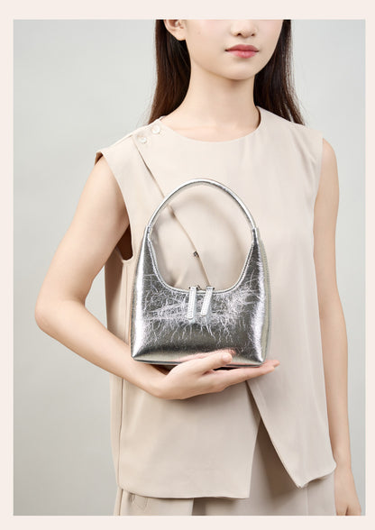 Model holding silver mini hobo bag in hand, front view