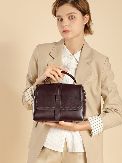 Model cradling the medium leather Boston bag with both hands at waist level