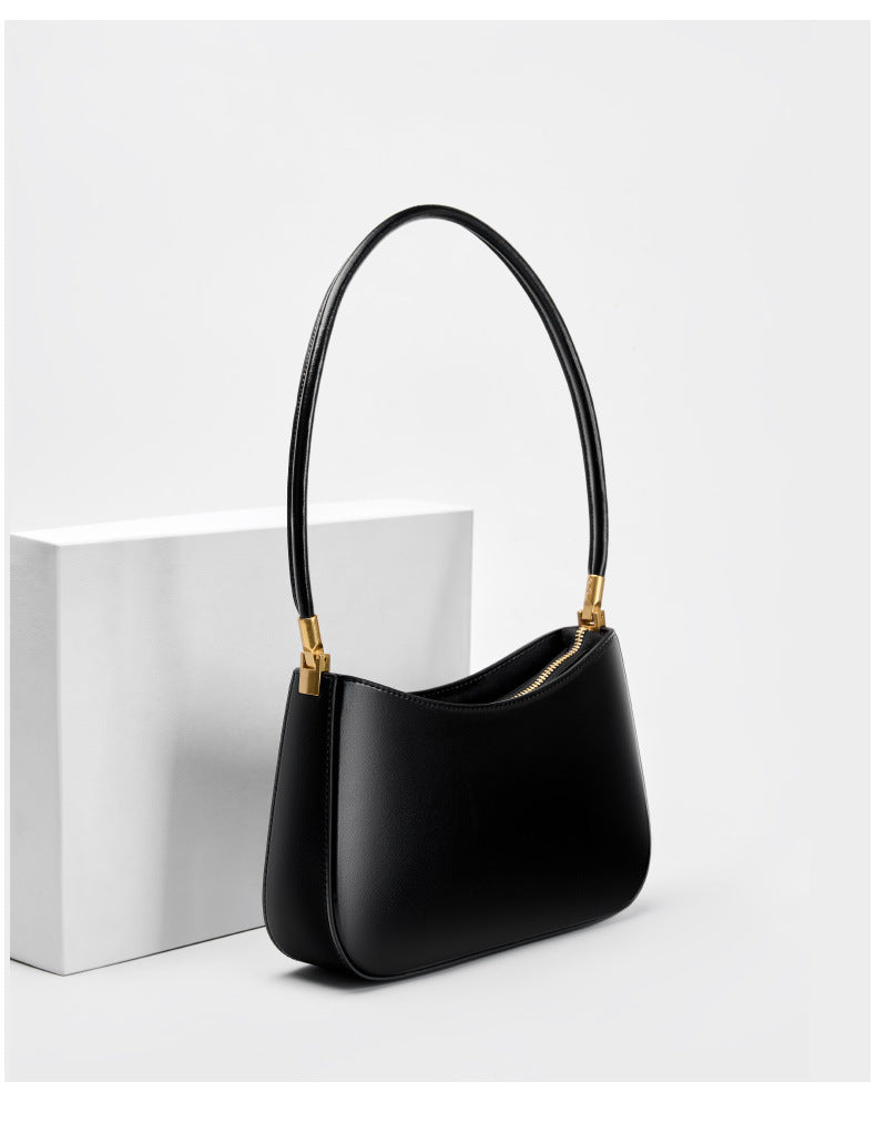 Black shoulder bag shown from a three-quarter angle on a white block