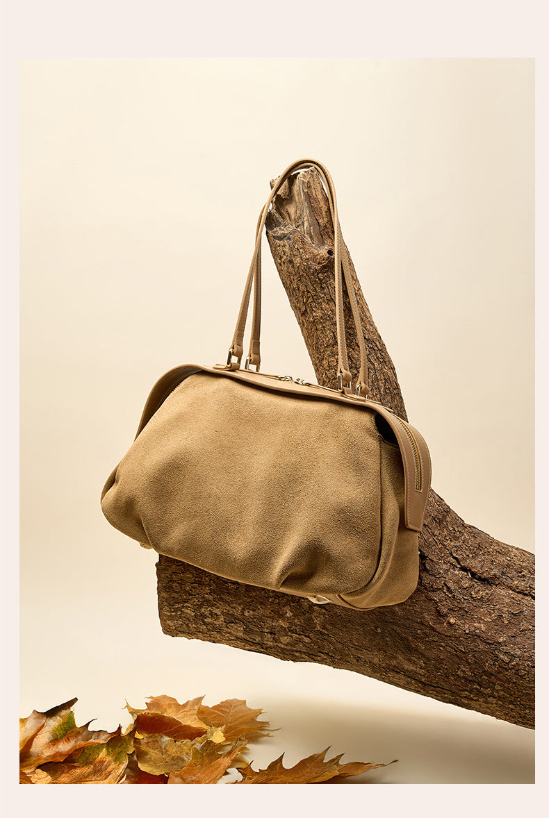 Khaki suede shoulder bag posed on a tree branch