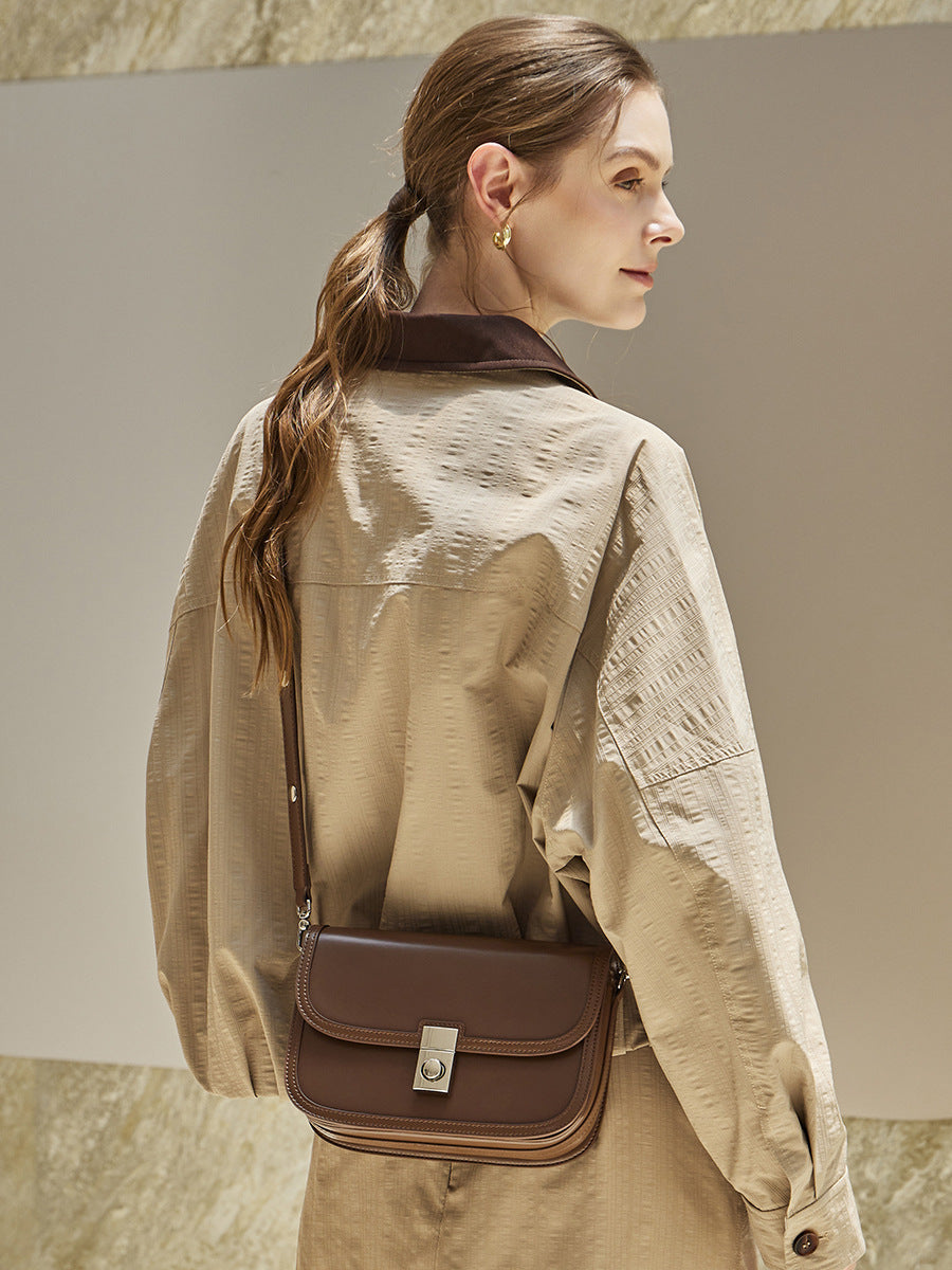 Side view of brown leather messenger bag styled with trench coat