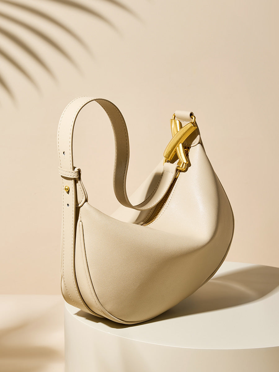 Off-white cowhide crescent underarm bag with strap detail on a beige podium