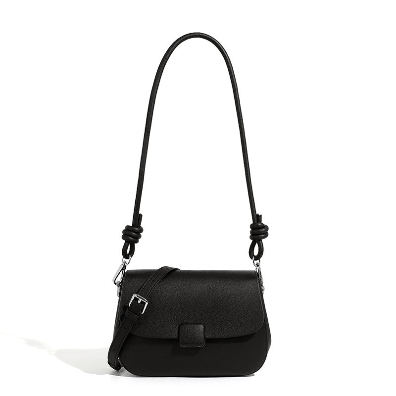 Black cowhide leather compact crossbody bag with turn-lock flap on white background