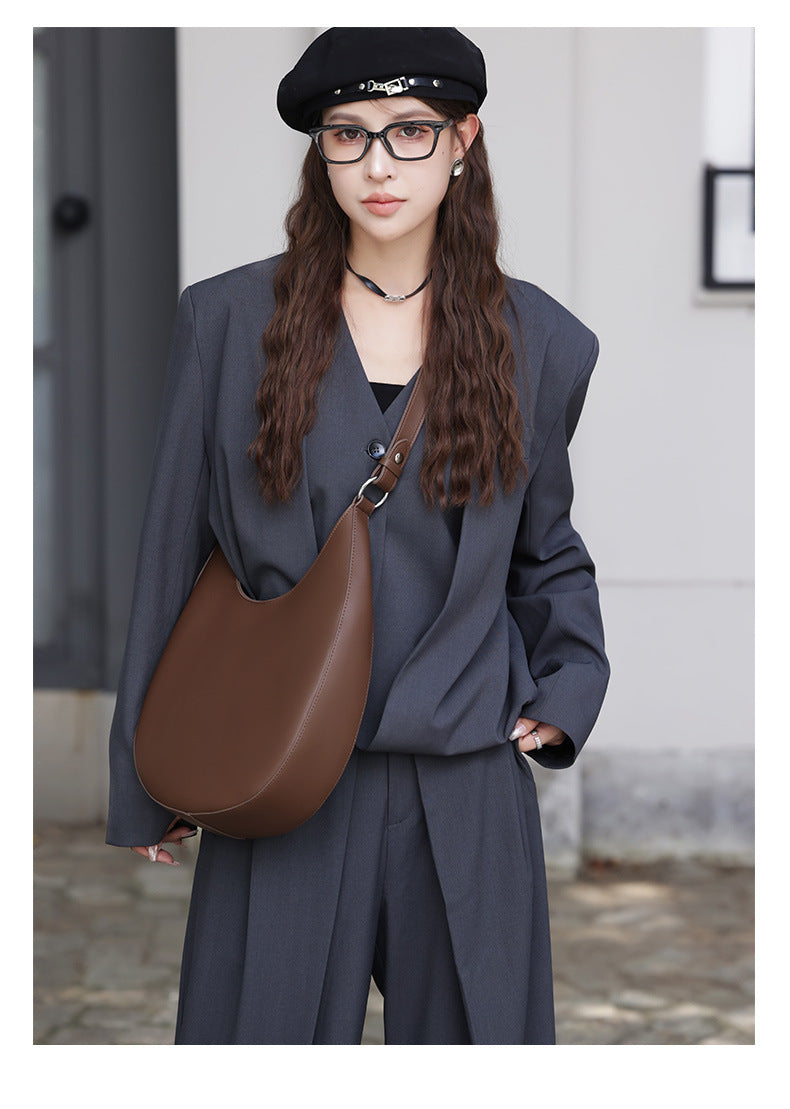Model wearing brown crescent hobo bag with gray suit and beret