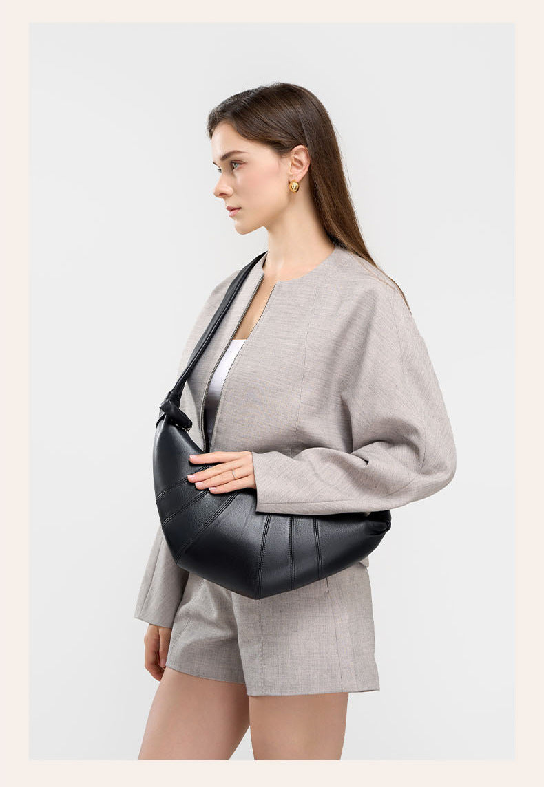 Model in gray outfit with black crescent bag under the arm