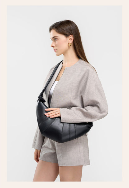 Model in gray outfit with black crescent bag under the arm