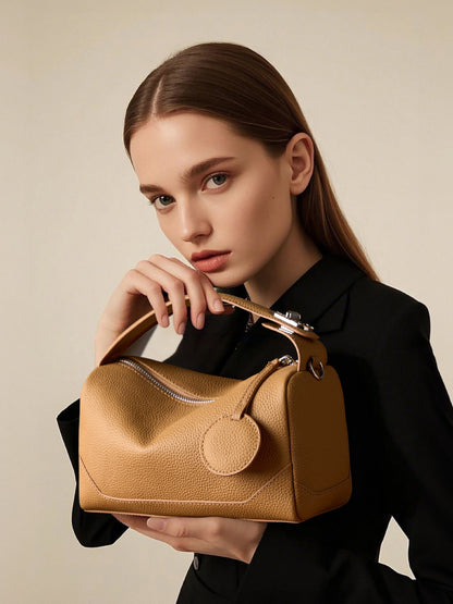 Model holding caramel mini Boston bag under top handle in studio portrait