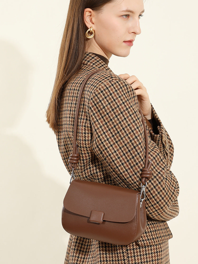 Side view of model wearing brown leather crossbody bag over houndstooth blazer