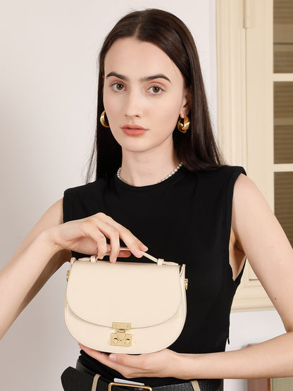 Model carrying cream saddle bag in hand at chest height