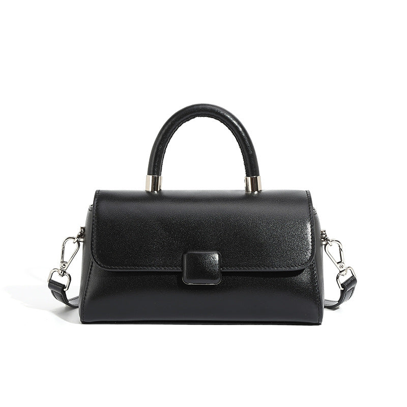 Black cowhide leather mini top-handle crossbody bag with flap closure on white background