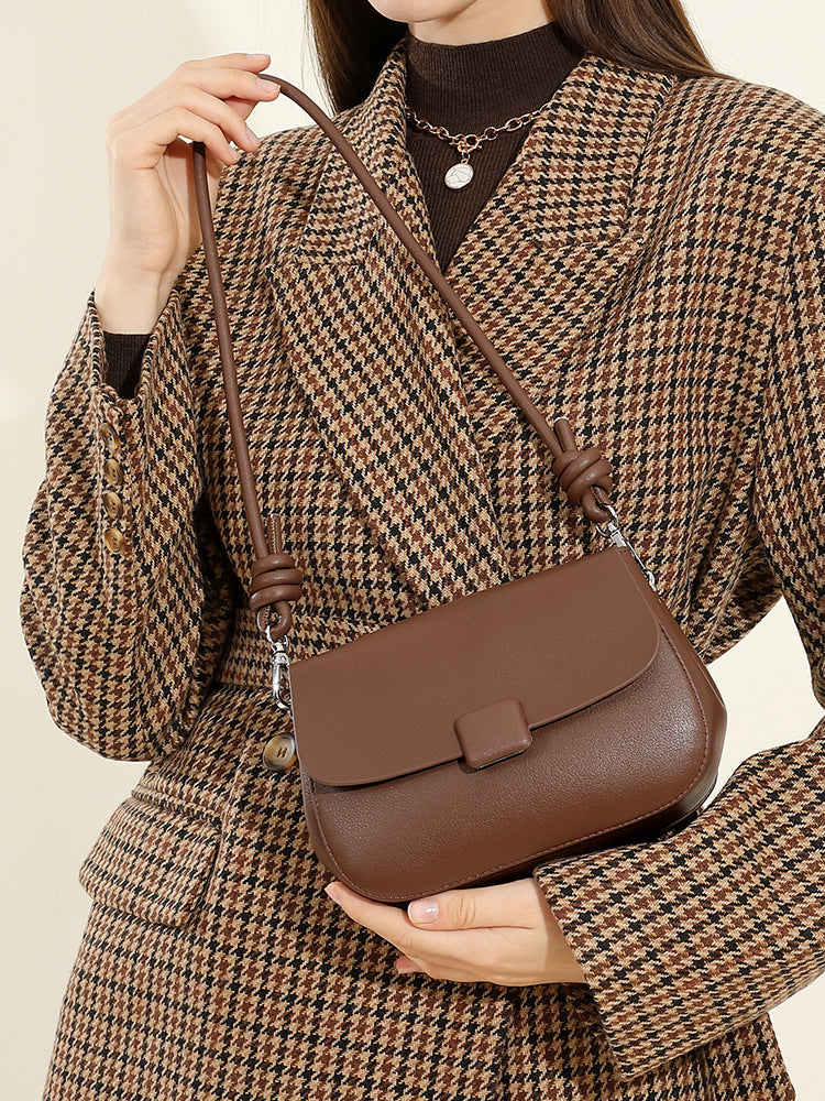 Close-up of model carrying brown leather crossbody bag across the body