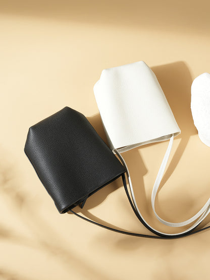 Flat lay of black and off-white mini bucket bags on beige surface