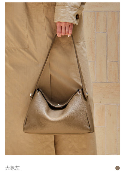Top-handle carry view of an elephant gray pebbled leather underarm bag with turn-lock closure
