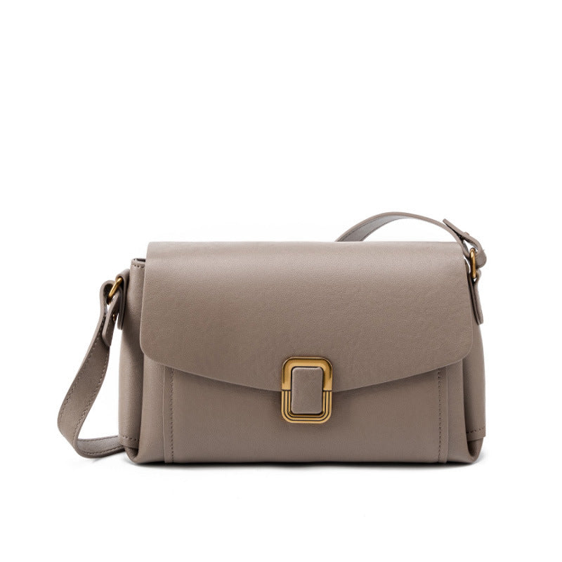 Gray cowhide leather crossbody bag with gold-tone buckle on white background