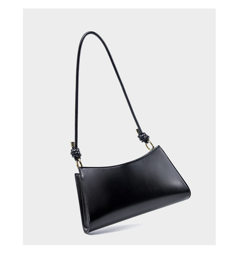 Side angle view of black leather underarm bag showing its slim profile