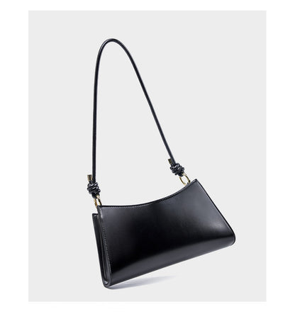 Side angle view of black leather underarm bag showing its slim profile