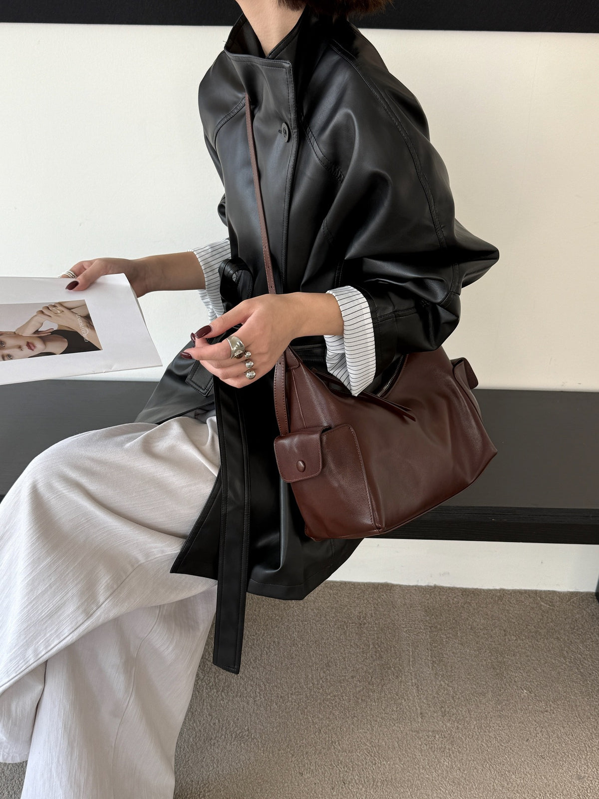 Brown shoulder bag shown with its zip closure and side pocket