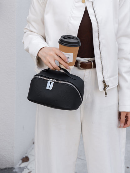 Black cowhide pouch carried by hand, showing its compact profile