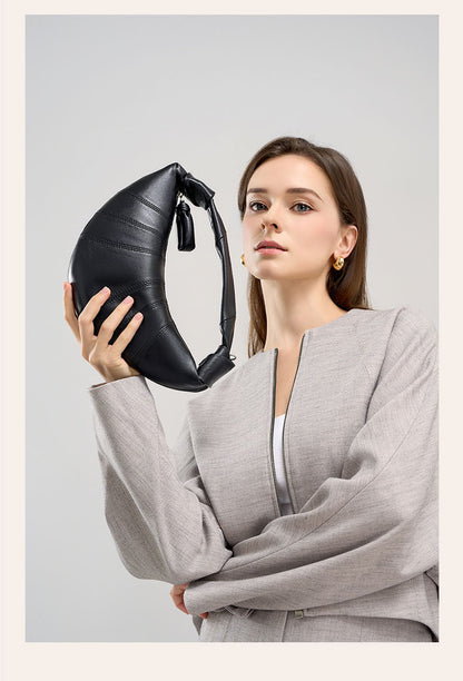 Model lifting black crescent bag to show knotted strap detail