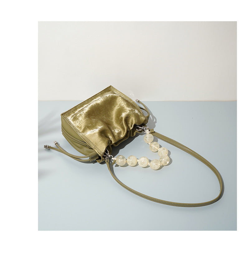 Champagne mini bucket bag resting at an angle on a neutral surface