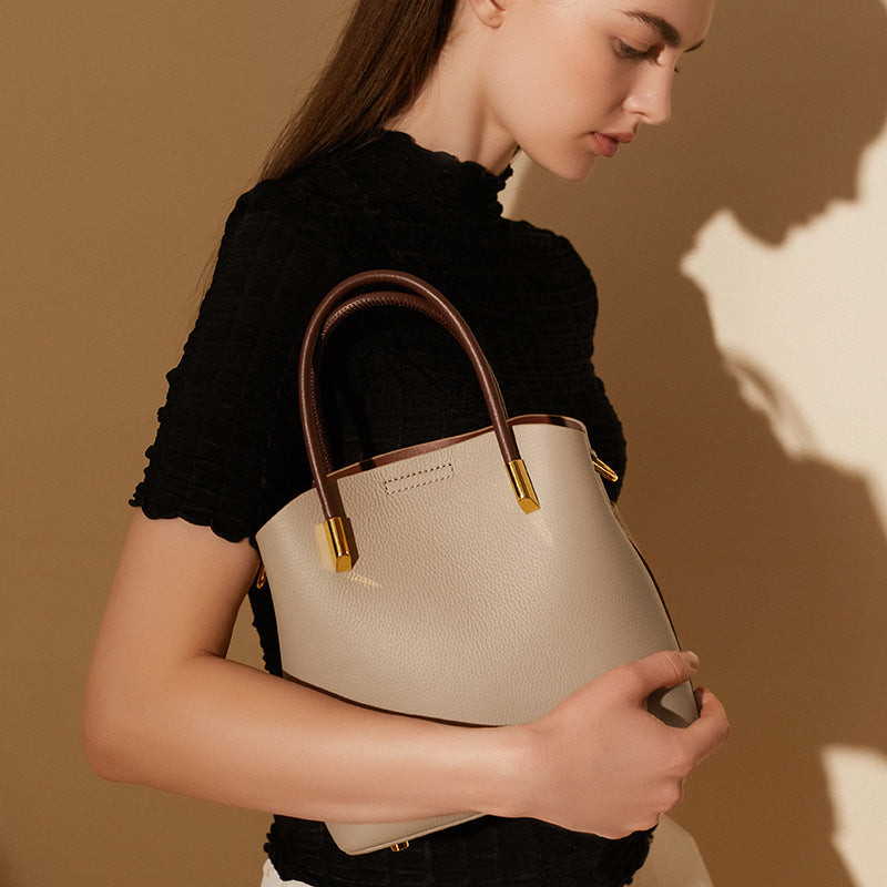 Gray bucket bag held in hand showing the structured silhouette