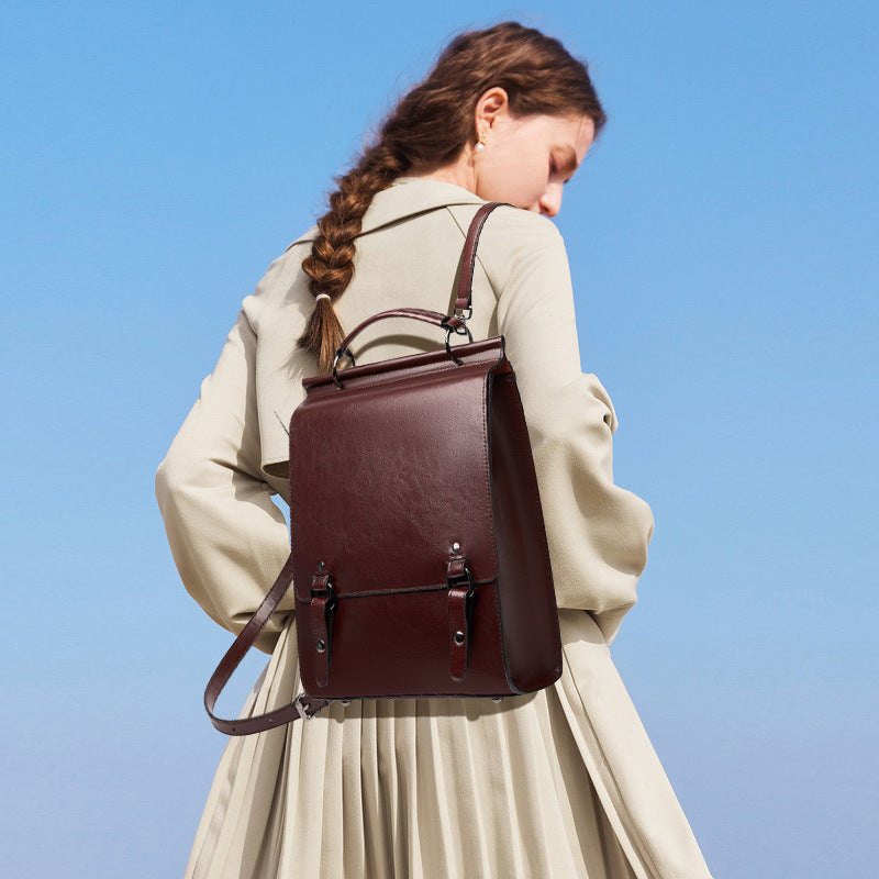 Brown leather backpack worn on one shoulder by model