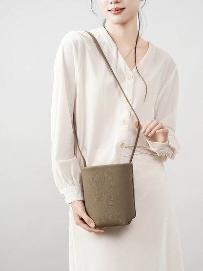 Model wearing elephant gray mini bucket crossbody bag with cream outfit