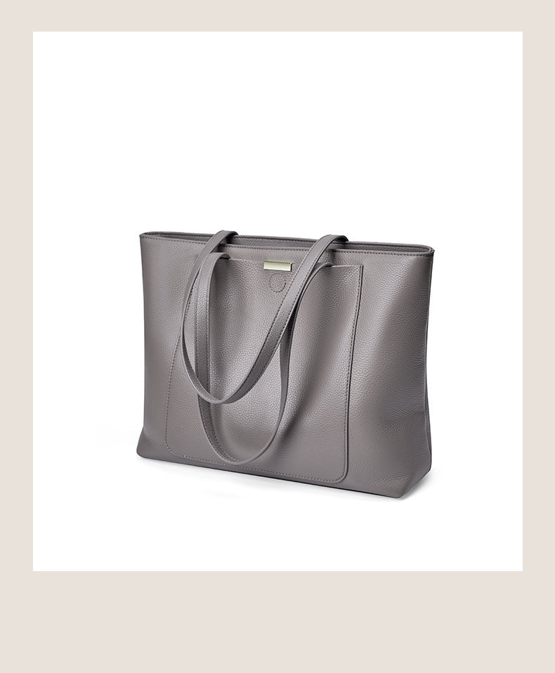 Angled front view of dark gray pebbled leather tote on a white surface