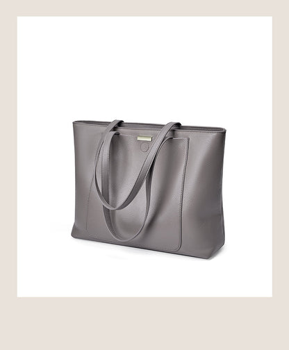 Angled front view of dark gray pebbled leather tote on a white surface