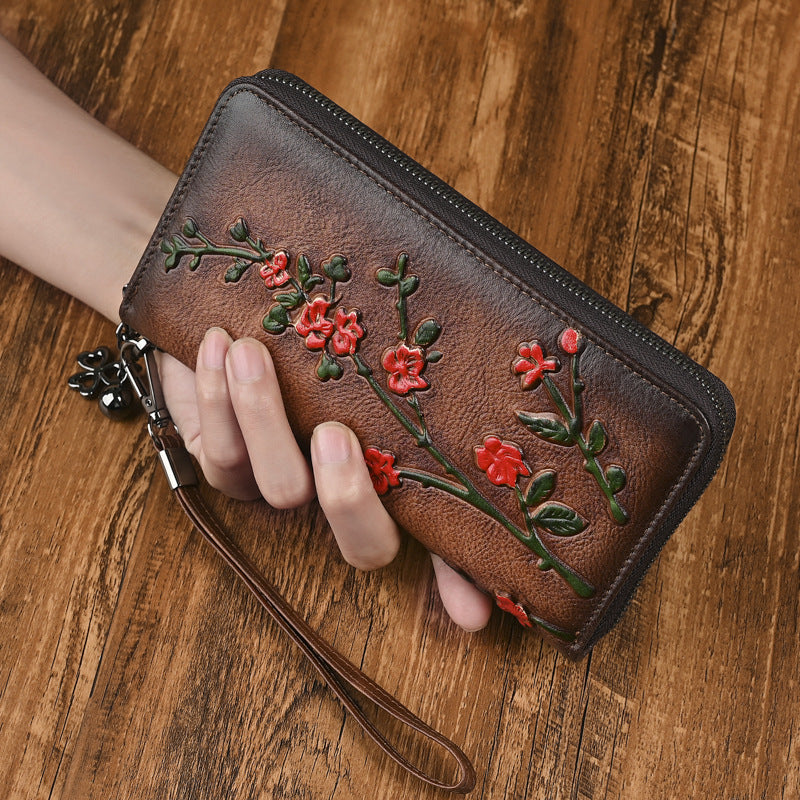 Brown floral wallet shown in hand with detachable wrist strap