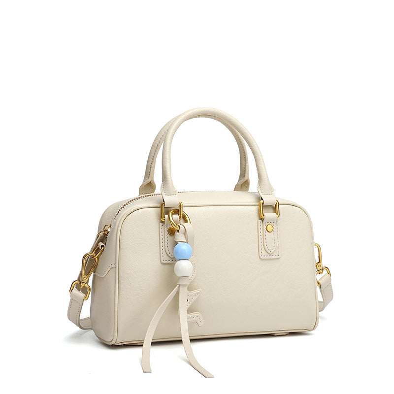 Cream cowhide leather pillow bag with double handles on a white background