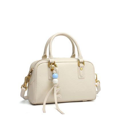 Cream cowhide leather pillow bag with double handles on a white background