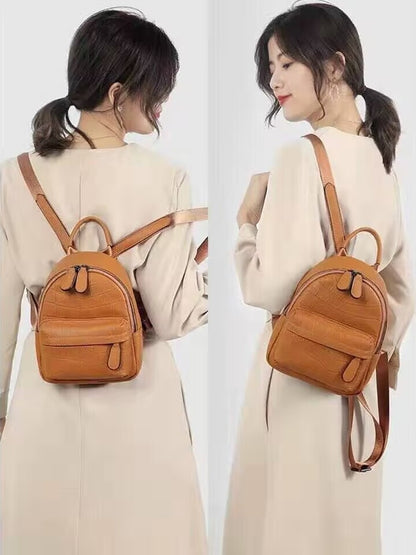 Woman wearing a tan mini backpack with adjustable-looking shoulder straps