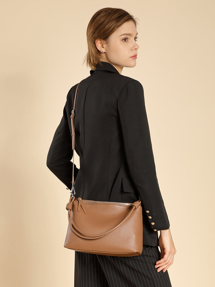 Back view of model in blazer carrying caramel leather tote on shoulder