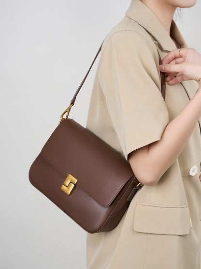Coffee cowhide crossbody bag worn crossbody by model in beige outfit