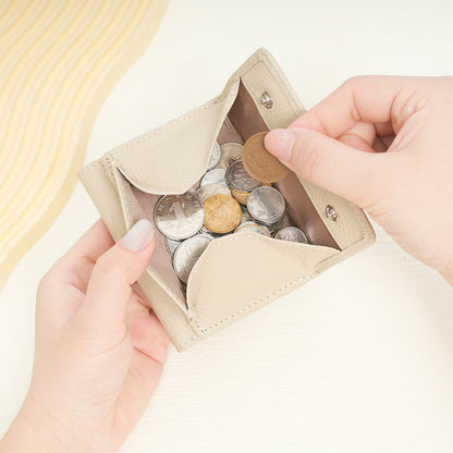 Hands holding open beige leather wallet showing coin pouch filled with coins