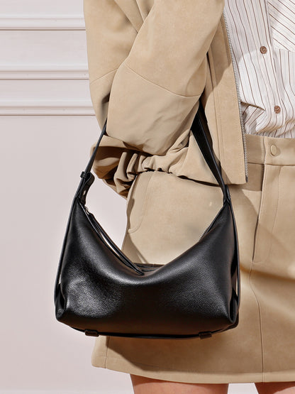 Close-up of black hobo bag worn on shoulder with beige outfit