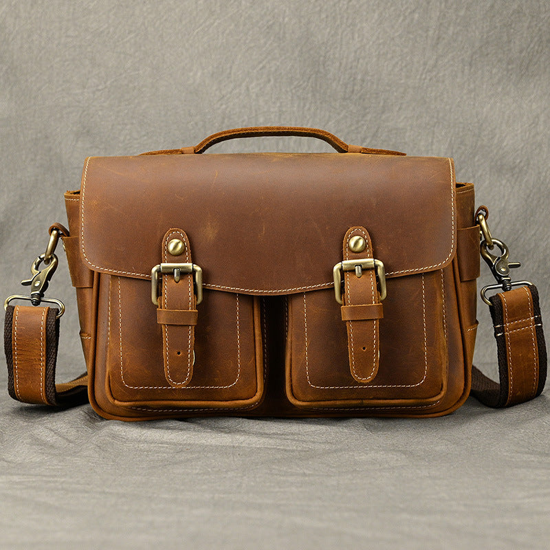 Brown leather camera bag shown with its shoulder strap