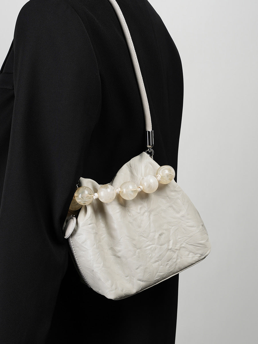 Off-white crinkle bag styled under the arm with a black blazer