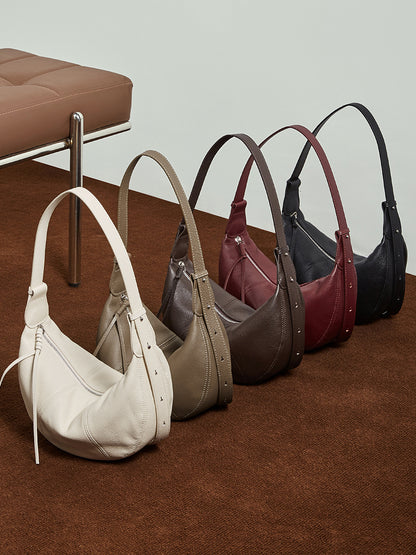 Five color lineup of cowhide crescent hobo bags on brown floor