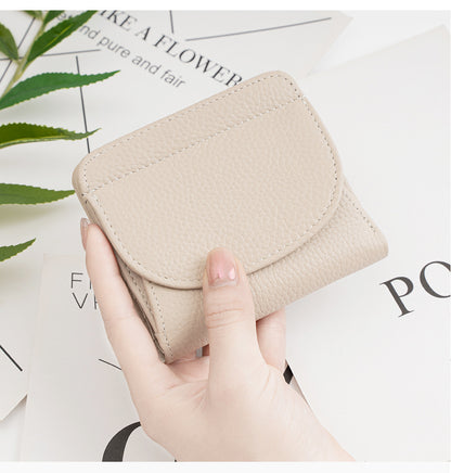 Hand holding ivory wallet over magazine with plant background