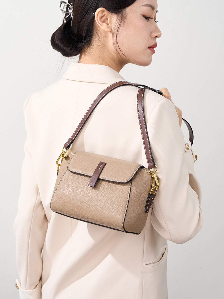 Model carrying khaki shell crossbody bag on the shoulder with a cream blazer