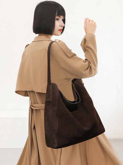 Model carrying the brown shoulder tote over a coat