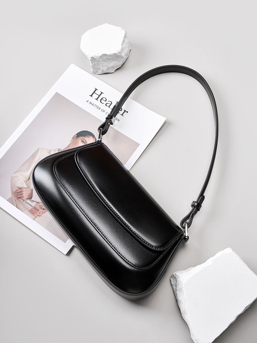 Lifestyle shot of the black leather baguette bag placed on a magazine