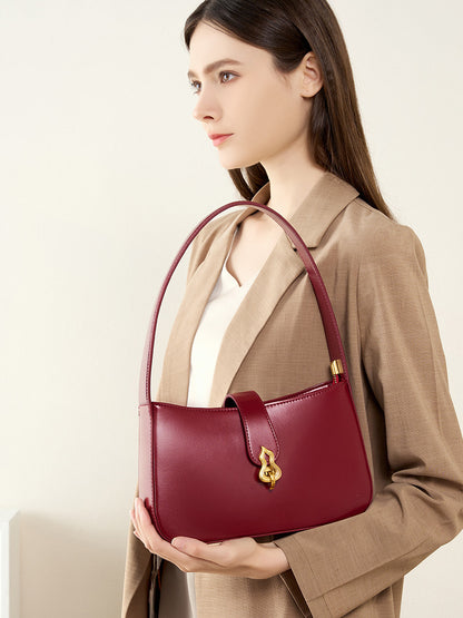 Front view of burgundy shoulder bag held in model hands