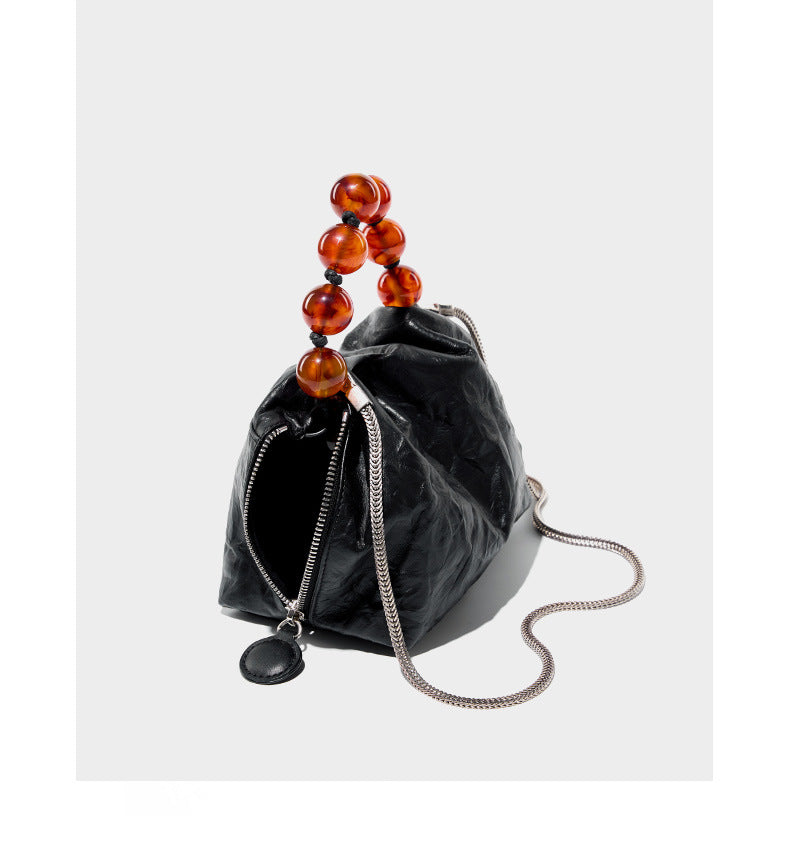Black crinkle bag shown with chain strap extended and zip detail