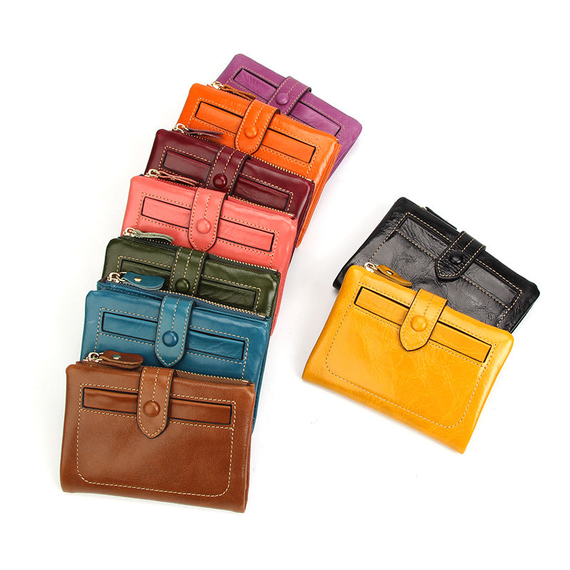Color lineup of nine vintage cowhide leather short wallets in orange, pink, yellow, green, teal, burgundy, purple, brown, and black