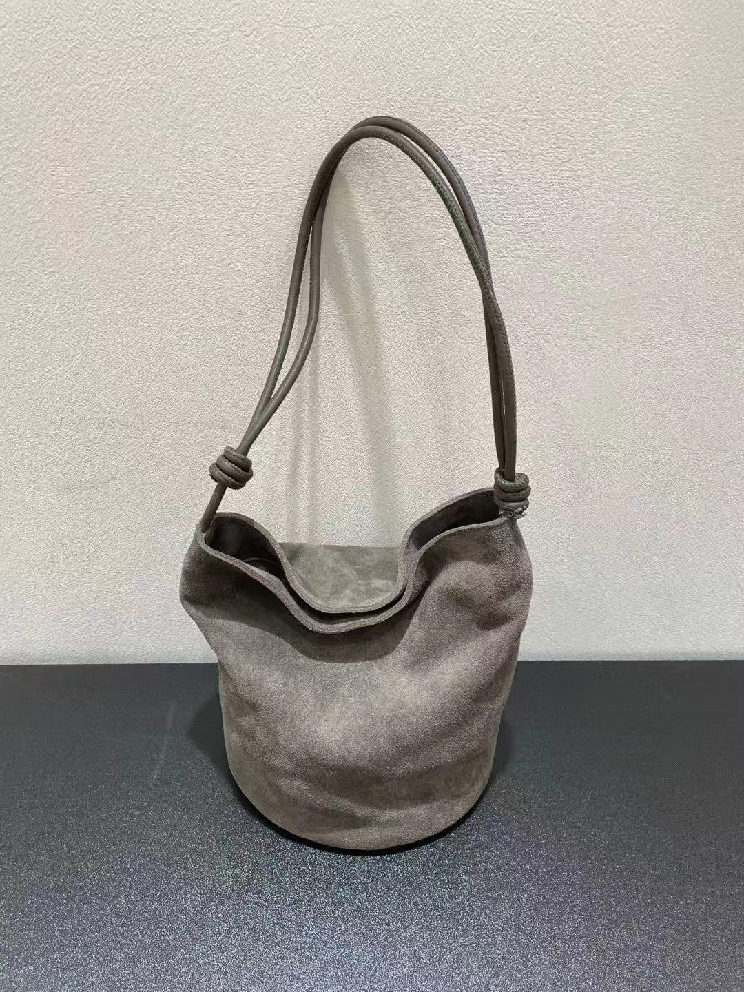 Gray suede bucket bag displayed upright