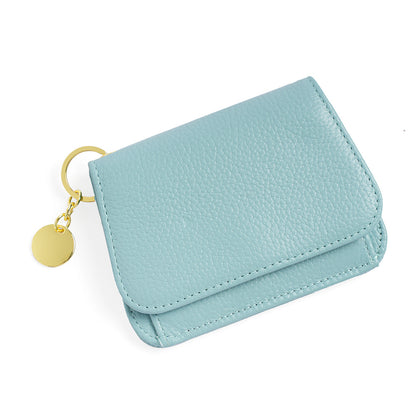 Light blue pebbled leather mini wallet with gold keyring charm on white background