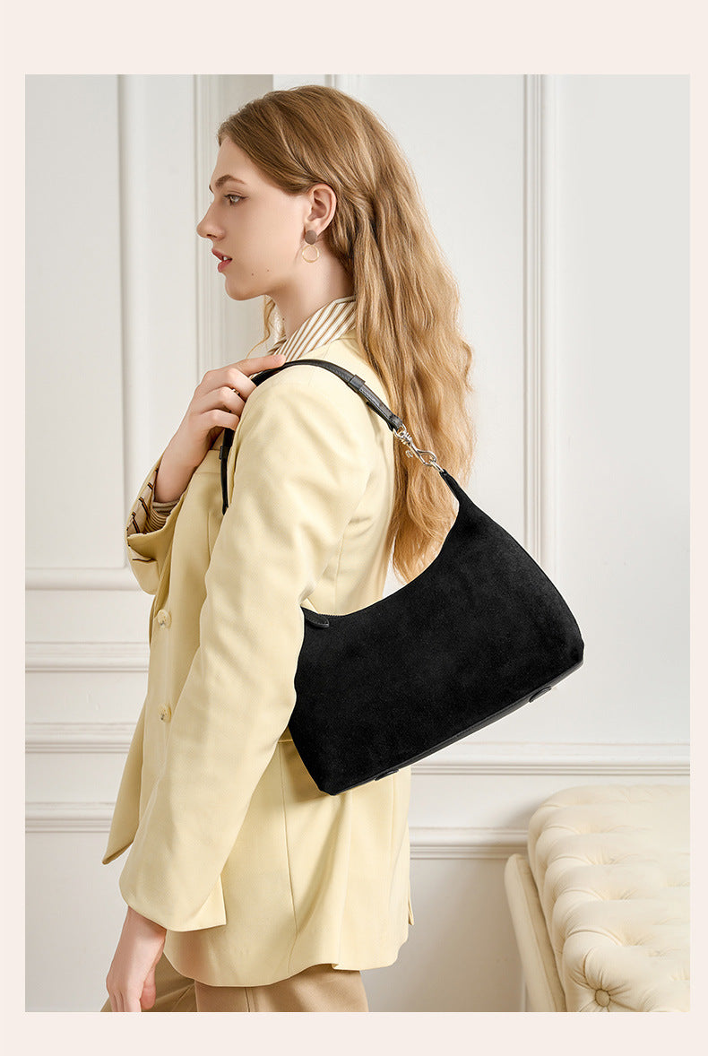Black shoulder bag worn over the shoulder in profile